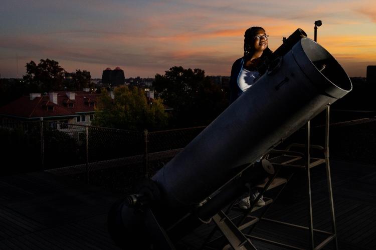 黄昏时分，一名学生站在瓦科天文台的大型望远镜后面